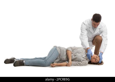 Medico in uniforme praticando il primo soccorso su donna su sfondo bianco Foto Stock
