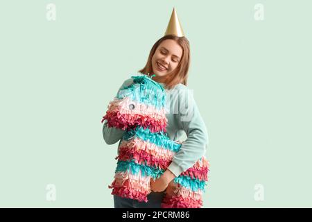 Giovane donna in cappello da festa con pinata messicana su sfondo verde Foto Stock