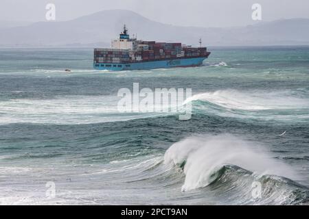 Una gigantesca nave da carico che naviga attraverso il mare del pacifico con onde che si infrangono al largo della costa della Nuova Zelanda. Foto Stock