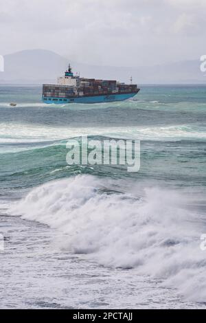 Una gigantesca nave da carico che naviga attraverso il mare del pacifico con onde che si infrangono al largo della costa della Nuova Zelanda. Foto Stock