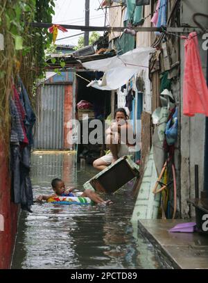 A mother sits by the door as a boy uses an inflatable tube to play in floodwaters which was inundated by tropical storm 'Bilis' at northern Manila suburb of Malabon Thursday July 13, 2006 in the Philippines. Classes remain suspended in metropolitan Manila for the second straight day Thursday as tropical storm 'Bilis' became a full-fledged typhoon dumping more rains as it headed towards Taiwan but not after leaving 12 people dead. The tropical storm also triggered several landslides in the northern Philippine city of Baguio burying homes and cars. (AP Photo/Bullit Marquez)