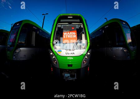 Hannover, Germania. 14th Mar, 2023. I veicoli della ferrovia leggera della compagnia di trasporto Hanover üstra sono parcheggiati presso il deposito di Glocksee - un cartello riporta "avvertimento sciopero oggi". A causa dei rinnovati scioperi di allarme, anche la popolazione della bassa Sassonia deve prepararsi a numerose restrizioni il martedì. Le linee üstra di Hannover sono in sciopero. (Ripresa con obiettivo fisheye) Credit: Moritz Frankenberg/dpa/Alamy Live News Foto Stock