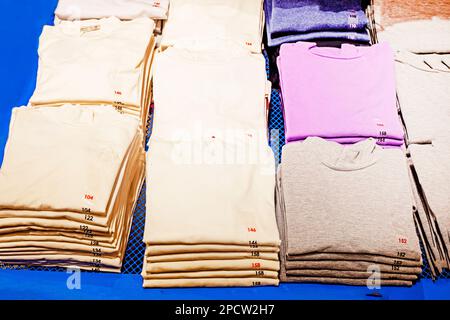 magliette bianche da scuola e altri colori nel negozio. ritorno a scuola Foto Stock