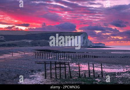 Drammatica alba dal cielo rosso sulla bassa marea di Cuckmere Haven sulla costa orientale del Sussex, Inghilterra sud-orientale, Regno Unito Foto Stock