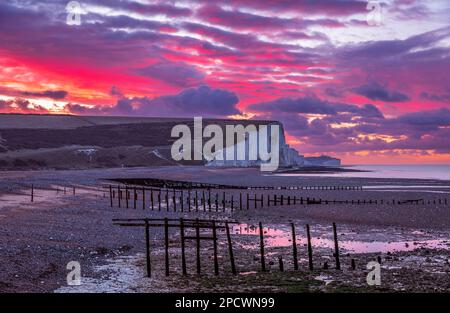 Drammatica alba dal cielo rosso sulla bassa marea di Cuckmere Haven sulla costa orientale del Sussex, Inghilterra sud-orientale, Regno Unito Foto Stock