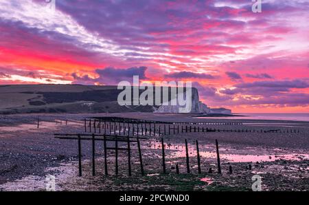 Drammatica alba dal cielo rosso sulla bassa marea di Cuckmere Haven sulla costa orientale del Sussex, Inghilterra sud-orientale, Regno Unito Foto Stock