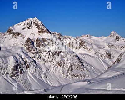 Questo splendido paesaggio mostra una catena montuosa innevata con la sua vetta più alta e chiara sullo sfondo invernale Foto Stock