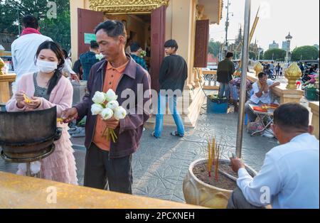 Phnom Penh, Cambogia-Dicembre 23 2023: Lungo il Riverside Promenade, devout Khmer uomini, donne e famiglie si riuniscono nel relativamente fresco, tardo pomeriggio Foto Stock