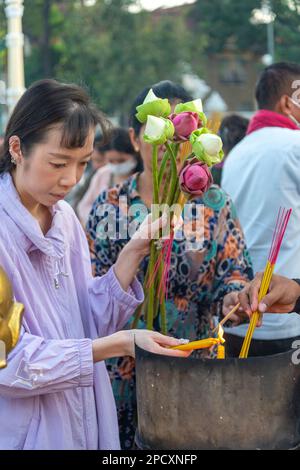 Phnom Penh, Cambogia-Dicembre 23 2023: Lungo il Riverside Promenade, devout Khmer uomini, donne e famiglie si riuniscono nel relativamente fresco, tardo pomeriggio Foto Stock