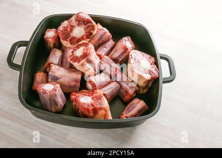 Pezzi di coda di bue crude con osso in un vassoio nero, carne ricca di gelatina tradizionale per stufato a cottura lenta o base di brodo per zuppa di coda di bue, spazio copia, selezionato Foto Stock