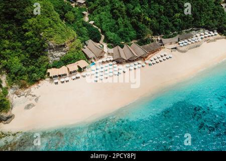 Vista aerea dell'oceano blu e del lussuoso resort sulla spiaggia con ombrelloni a Bali Foto Stock