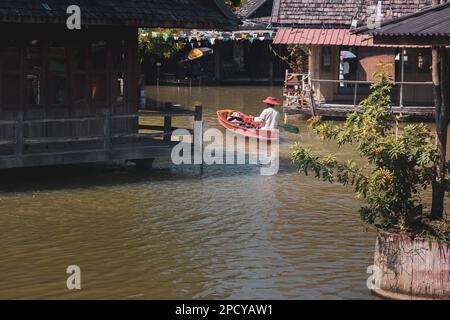 Mercato galleggiante di Pattaya, giornata di sole al mercato galleggiante di Pattaya, Thailandia, dove i turisti in barca indossano un cappello tradizionale godono della scena locale Foto Stock