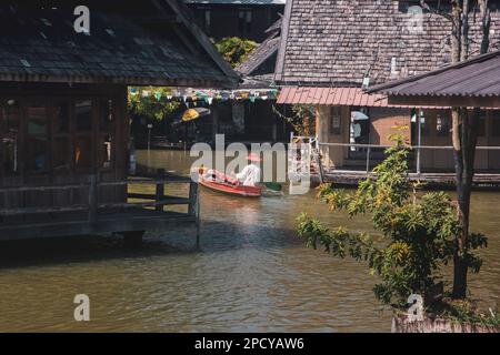 Mercato galleggiante di Pattaya, giornata di sole al mercato galleggiante di Pattaya, Thailandia, dove i turisti in barca indossano un cappello tradizionale godono della scena locale Foto Stock