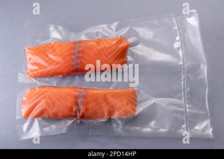 Fette di salmone confezionate sottovuoto sigillate per una cucina sous vide su sfondo grigio Foto Stock