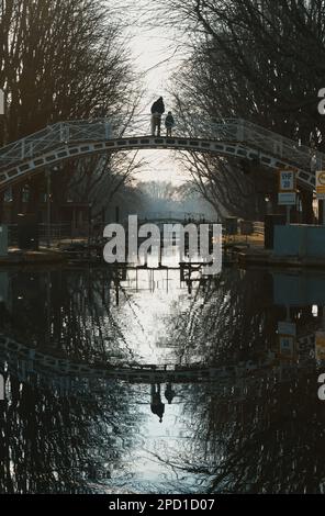 Famiglia in piedi su Un ponte pedonale guardando Un blocco su Una Misty Primavera mattina, Canal Saint Martin Parigi Foto Stock