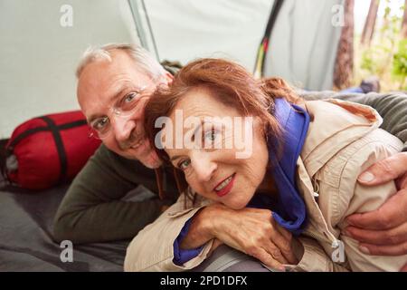 Felice coppia anziana innamorata sdraiata in tenda sul campeggio in natura Foto Stock