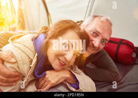 Felice coppia anziana innamorata sdraiata in tenda sul campeggio in estate Foto Stock