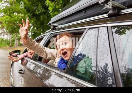 Ritratto di donne anziane spensierate che ondolano le mani attraverso i finestrini mentre si siedono in auto durante il viaggio su strada Foto Stock