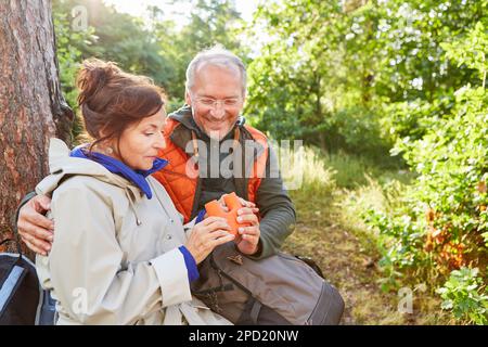 Uomo e donna sorridenti che guardano i binocoli mentre esplorano la foresta nelle vacanze estive Foto Stock