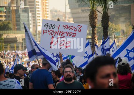 TEL AVIV, ISRAELE - 01 marzo 2023: I manifestanti antigovernative detengono bandiere israeliane mentre marciano durante una manifestazione contro il primo ministro israeliano Foto Stock