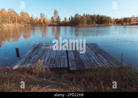 Una piattaforma in legno sulla riva di uno stagno o lago. Foto Stock