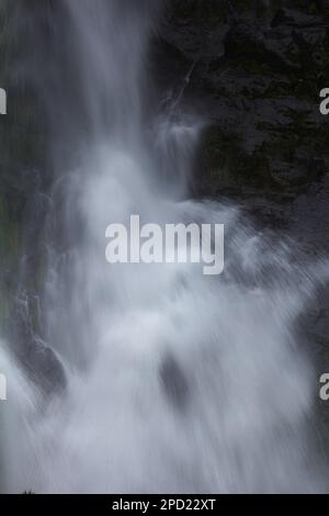 Una cascata naturale scorre lungo una lunga linea da una scogliera in una valle spruzzante. Foto Stock