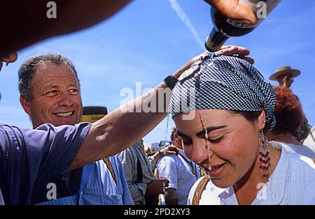 Sacerdote battezzando un pellegrino con il vino Manzanilla, tra il Palazzo Doñana e il villaggio Rocio, Romeria del Rocio, pellegrini in cammino per il Doñana Na Foto Stock