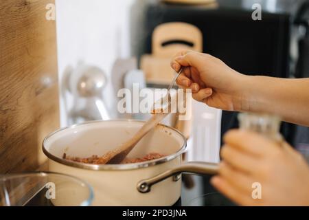 Il primo piano della donna aggiunge condimento piccante. Concetto di cibo fatto in casa. Cucina Foto Stock