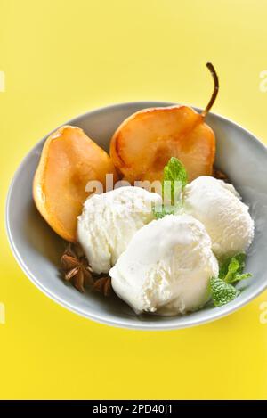 Gelato con pere in camicia in ciotola su fondo giallo. Vista ravvicinata Foto Stock