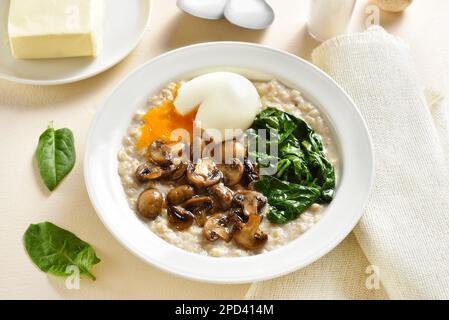 Farina d'avena di funghi e spinaci sul piatto su fondo di pietra chiara. Vista ravvicinata Foto Stock
