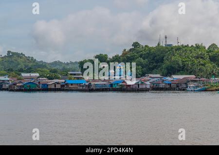 Vista dal traghetto per Waisai a Sorong con barche e case e una moschea Foto Stock