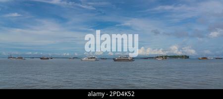 Vista dal traghetto a Waisai a Sorong con crociere e barche da tour, cielo blu sullo sfondo, spazio copia Foto Stock