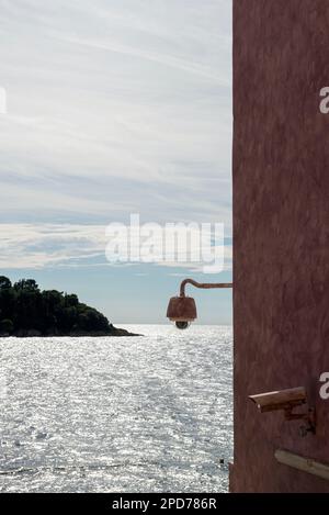 Sorveglianza a Rovigno, Croazia; due videocamere su pareti dipinte di rosso con mare scintillante argentato e isola sullo sfondo Foto Stock