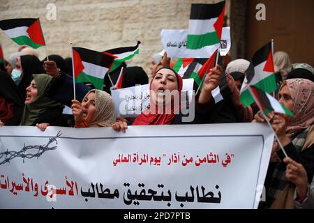 Città di Gaza, Palestina. 14th marzo 2023. Le donne palestinesi detengono la loro bandiera nazionale durante una manifestazione a sostegno dei prigionieri palestinesi detenuti nelle carceri israeliane, alcuni dei quali stanno osservando uno sciopero della fame, al di fuori del quartier generale della missione del Comitato Internazionale della Croce Rossa (CICR) a Gaza City. Foto Stock