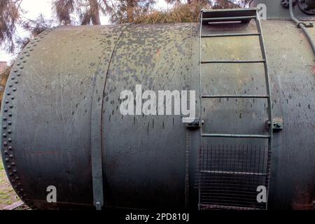 un vecchio frammento di vagone arrugginito del treno del combustibile dell'annata con una scala Foto Stock