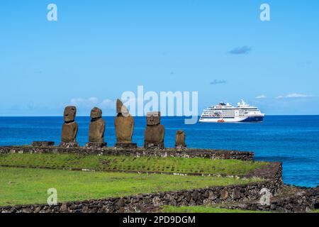 Isola di Pasqua, Cile - 5 marzo 2023: Statue di moai su AHU Vai Ure con una nave da crociera sullo sfondo del complesso di Tahai sull'isola di Pasqua, Cile. Foto Stock