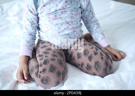 Bambino seduto W postura sul letto, cattivo concetto di postura seduta Foto Stock
