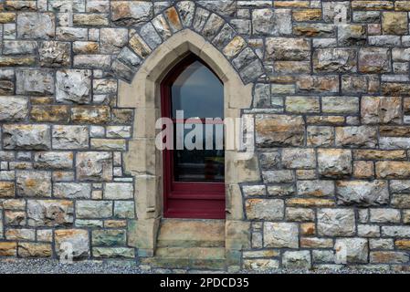 Una piccola, bella finestra in stile gotico su un muro di pietra del castello Foto Stock