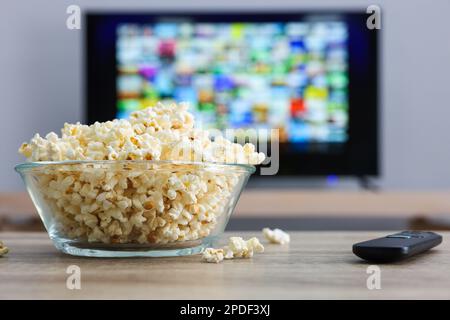 Ciotola di popcorn e telecomando TV sul tavolo all'interno Foto Stock