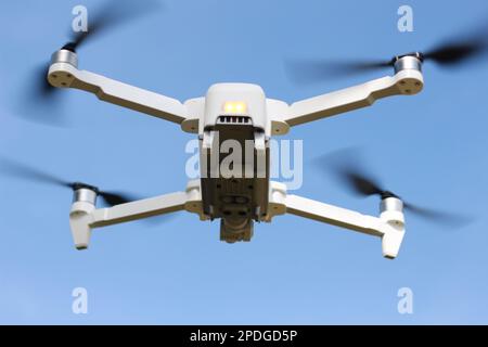 una foto di un drone che vola con un'elica sfocata su uno sfondo cielo blu. concetto di tecnologia fotografica. Foto Stock