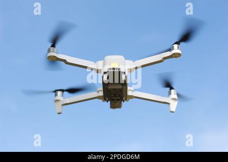 una foto di un drone che vola con un'elica sfocata su uno sfondo cielo blu. concetto di tecnologia fotografica. Foto Stock