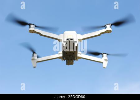 una foto di un drone che vola con un'elica sfocata su uno sfondo cielo blu. concetto di tecnologia fotografica. Foto Stock