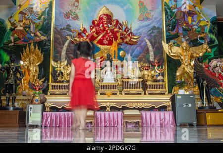 Motion Blur ragazza cammina di fronte a un altare in un tempio buddista, Thailandia Foto Stock