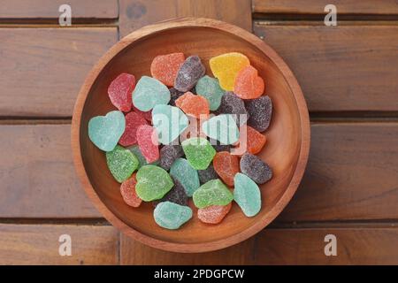 un primo piano di caramelle gommose di vari colori e sapori di frutta servite in una ciotola di legno. Foto Stock