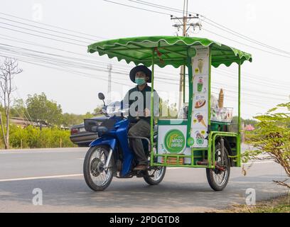 BANGKOK, THAILANDIA, MAR 11 2023, un fornitore di gelati guida una moto a tre ruote lungo una strada del villaggio Foto Stock