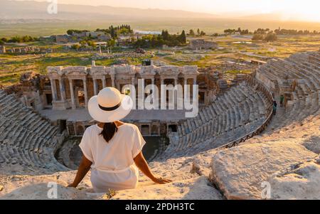 Hierapolis antica città di Pamukkale Turchia, una giovane donna con un cappello che guarda il tramonto dalle rovine UNESCO. Donne asiatiche che guardano il tramonto al vecchio Anfiteatro in Turchia Foto Stock