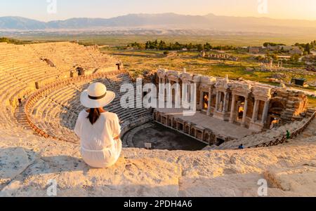 Hierapolis antica città di Pamukkale Turchia, una giovane donna con un cappello che guarda il tramonto dalle rovine UNESCO. Donne asiatiche che guardano il tramonto al vecchio Anfiteatro in Turchia Foto Stock