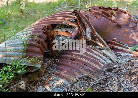 Arrugginito e decaduto, vecchio serbatoio d'acqua di ferro corrugato sdraiato a terra Foto Stock