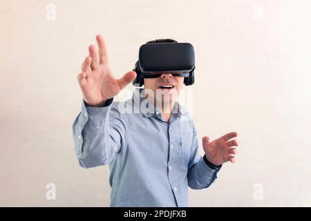realtà virtuale per il gioco tramite telefono e cellulare. uomo che indossa cuffie o occhiali per realtà virtuale su sfondo bianco, guarda intorno e cerca di toccare qualcosa, exci Foto Stock