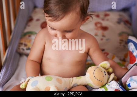 Ama la sua giraffa soffice. Una bambina cute del bambino nella sua greppia nel paese. Foto Stock